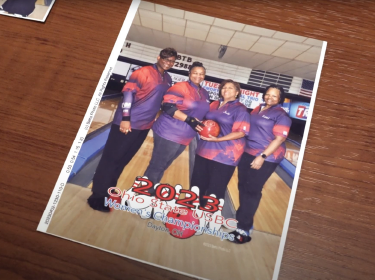 four women bowlers posing with bowling balls
